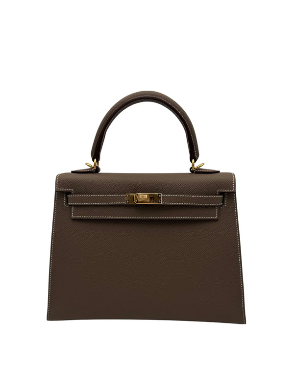Hermès Kelly 25 Epsom Etoupe con herrajes dorados, año 2025, cuero Epsom, incluye caja, dust bag, correa, llaves, candado e invoice.
