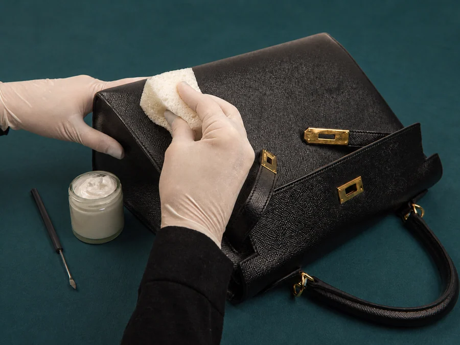 Hand-cleaning a black leather bag at the SPÀ